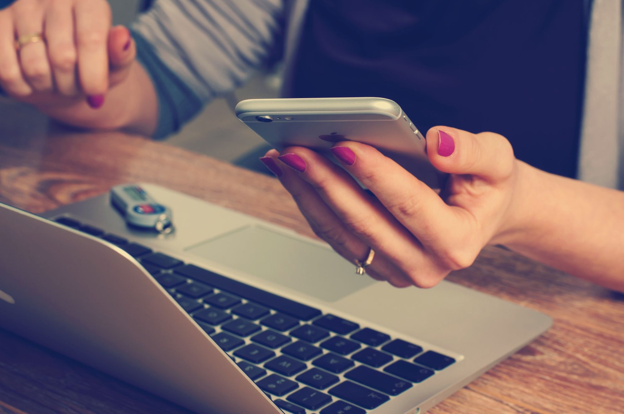 Person using smartphone while working on laptop, illustrating how customers search for restaurant menus online.